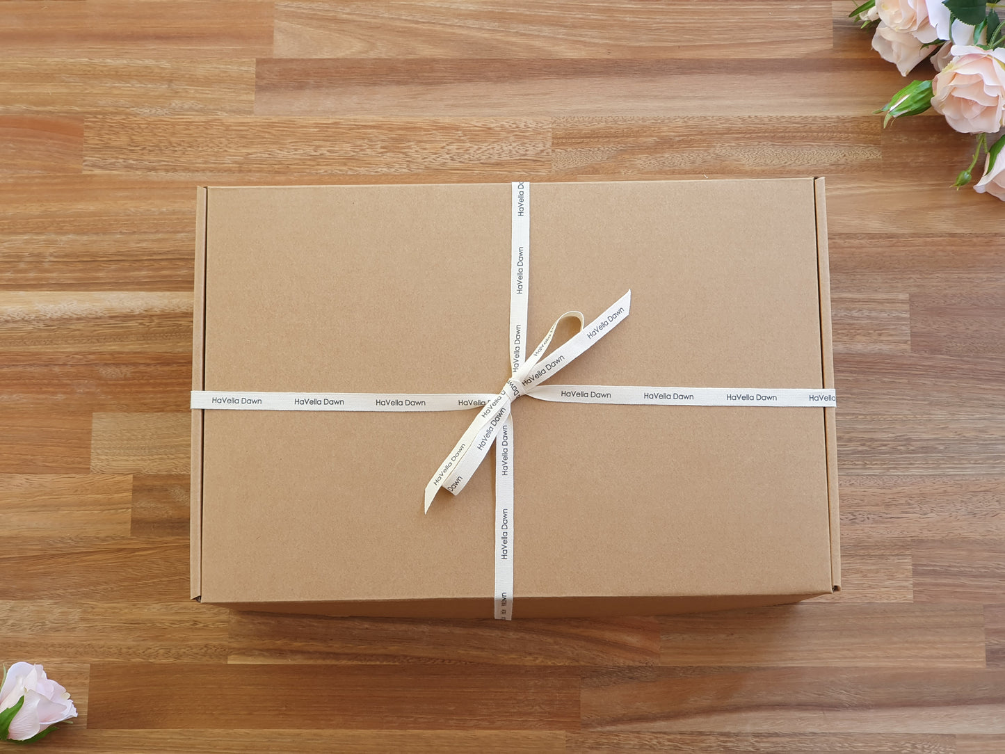 A square brown kraft paper gift box tied with a white ribbon printed with the brand name 'HaVella Dawn.