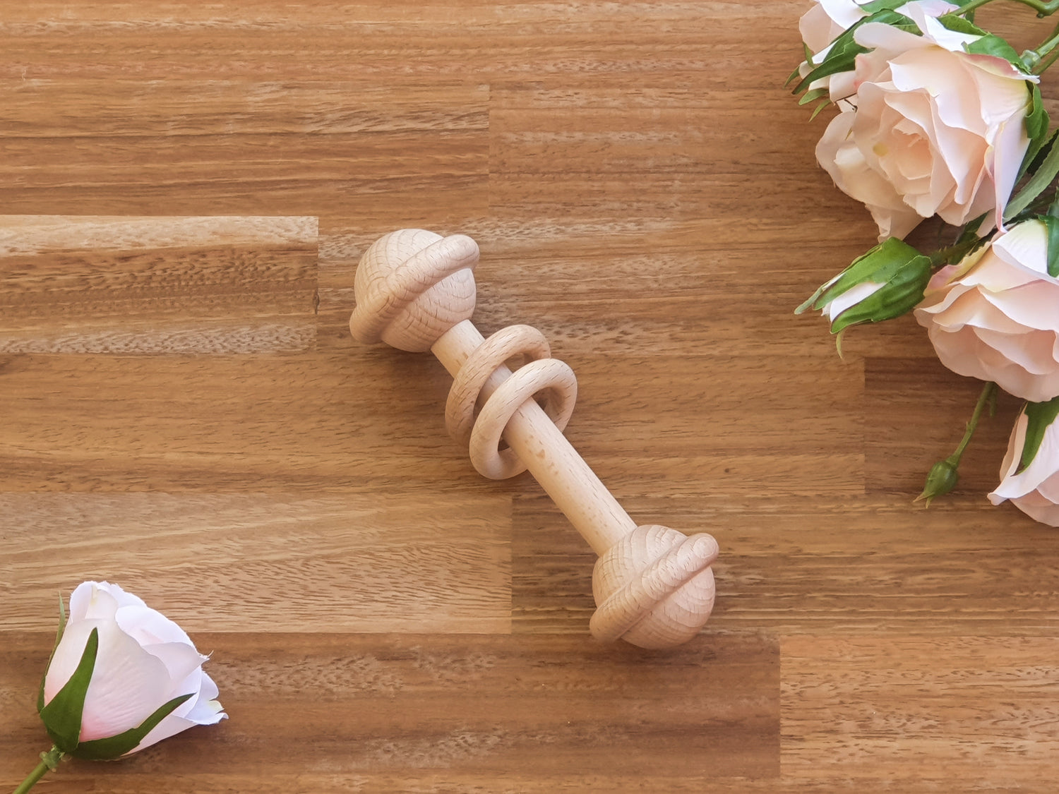 A natural wooden baby barbell rattle teething toy with 2 wooden rings.