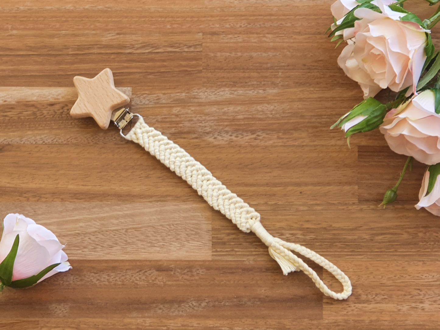 A baby pacifier chain with a natural wood star-shaped clip, a cream braided rope strap.