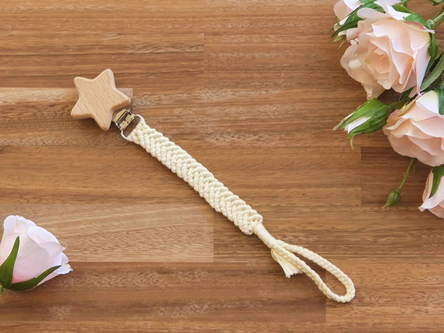 A baby pacifier chain with a natural wood star-shaped clip, a cream braided rope strap.