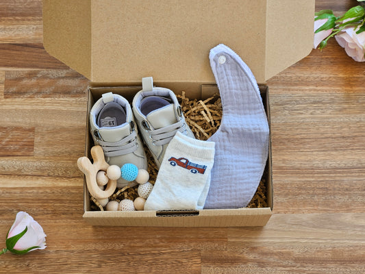 Baby shoe gift box includes grey walking boot. sock with truck image, beaded teether ring and grey waterproof bib