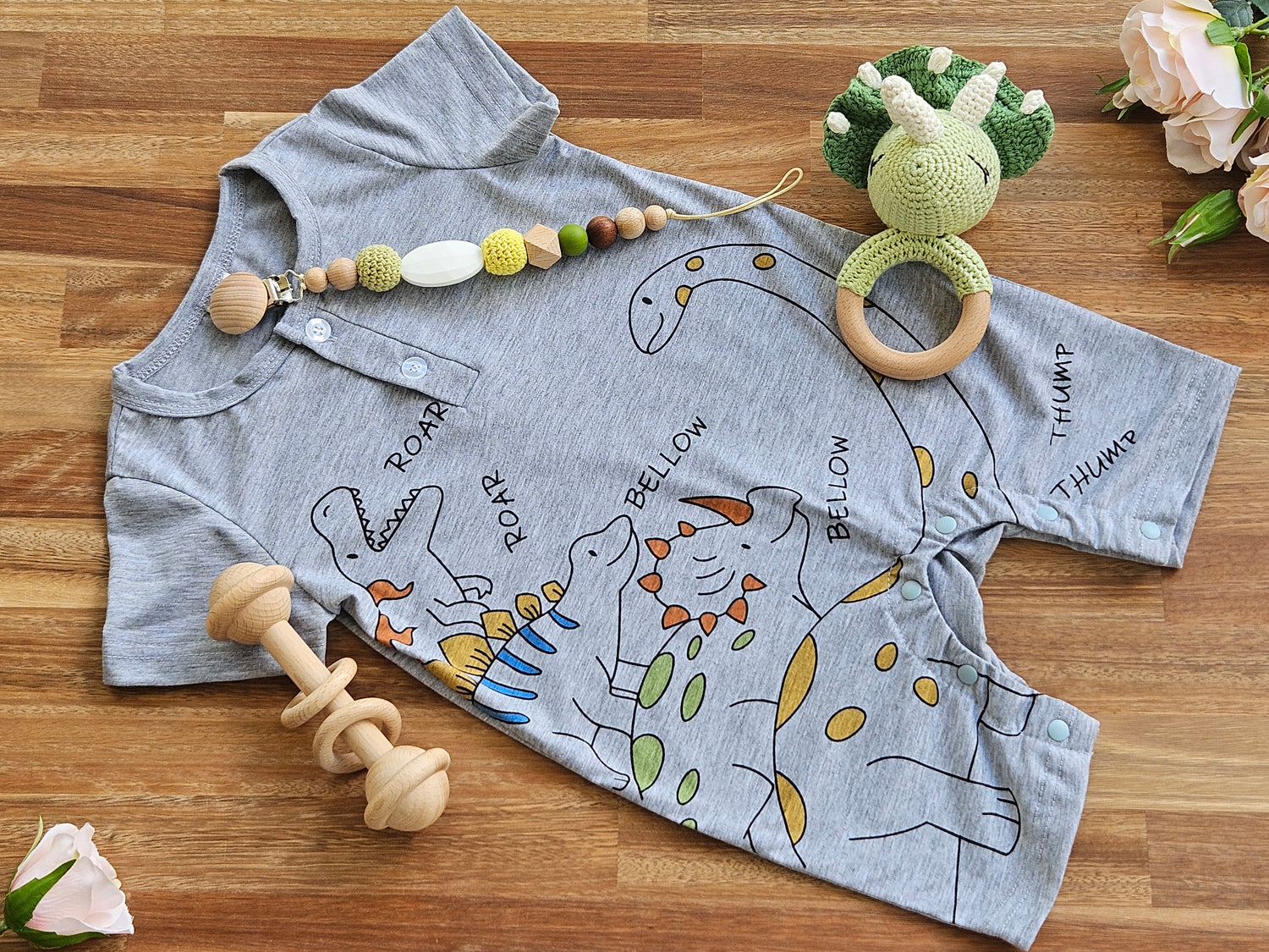 light weight grey dinosaur romper , crocheted dinosaur rattle, beaded pacifier chain and a wooden bar toy