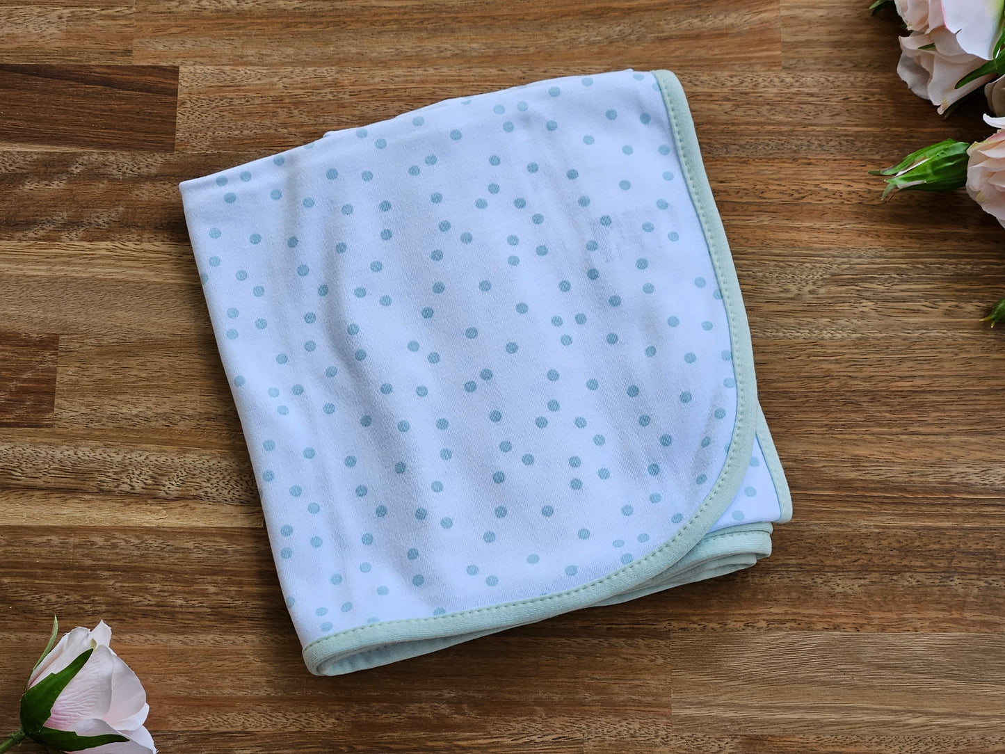 white cotton baby wrap with pale green spots.