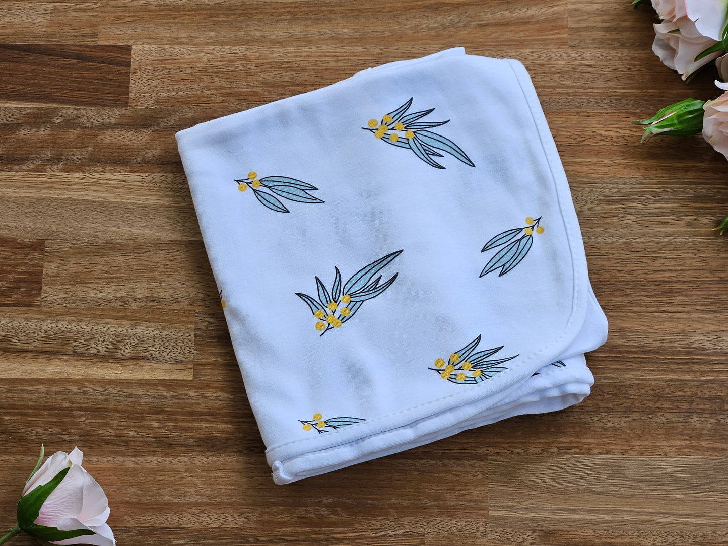 White cotton baby wrap with green and yellow wattle print.