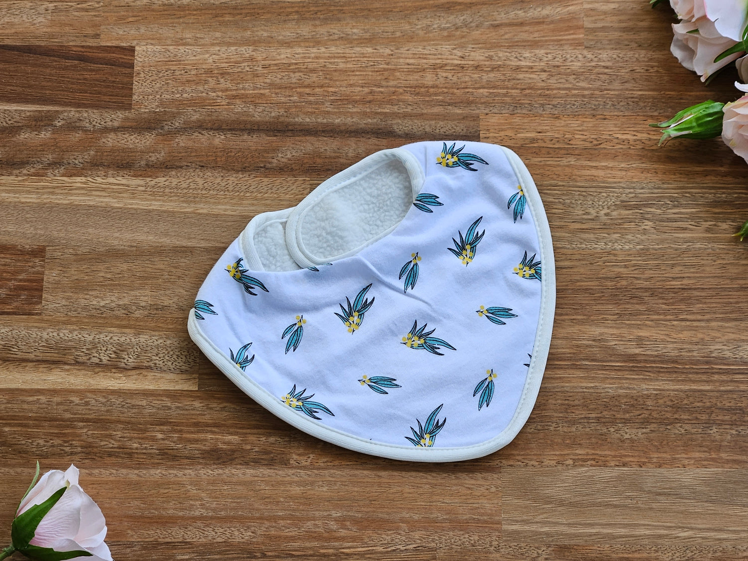 White cotton baby bib with green and yellow wattle print,