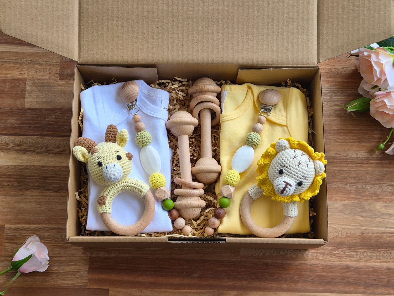 A baby gift set . The set includes a white and yellow baby romper, wooden baby toys, bead pacifier chain, and two crocheted lion and giraffe baby rattles.