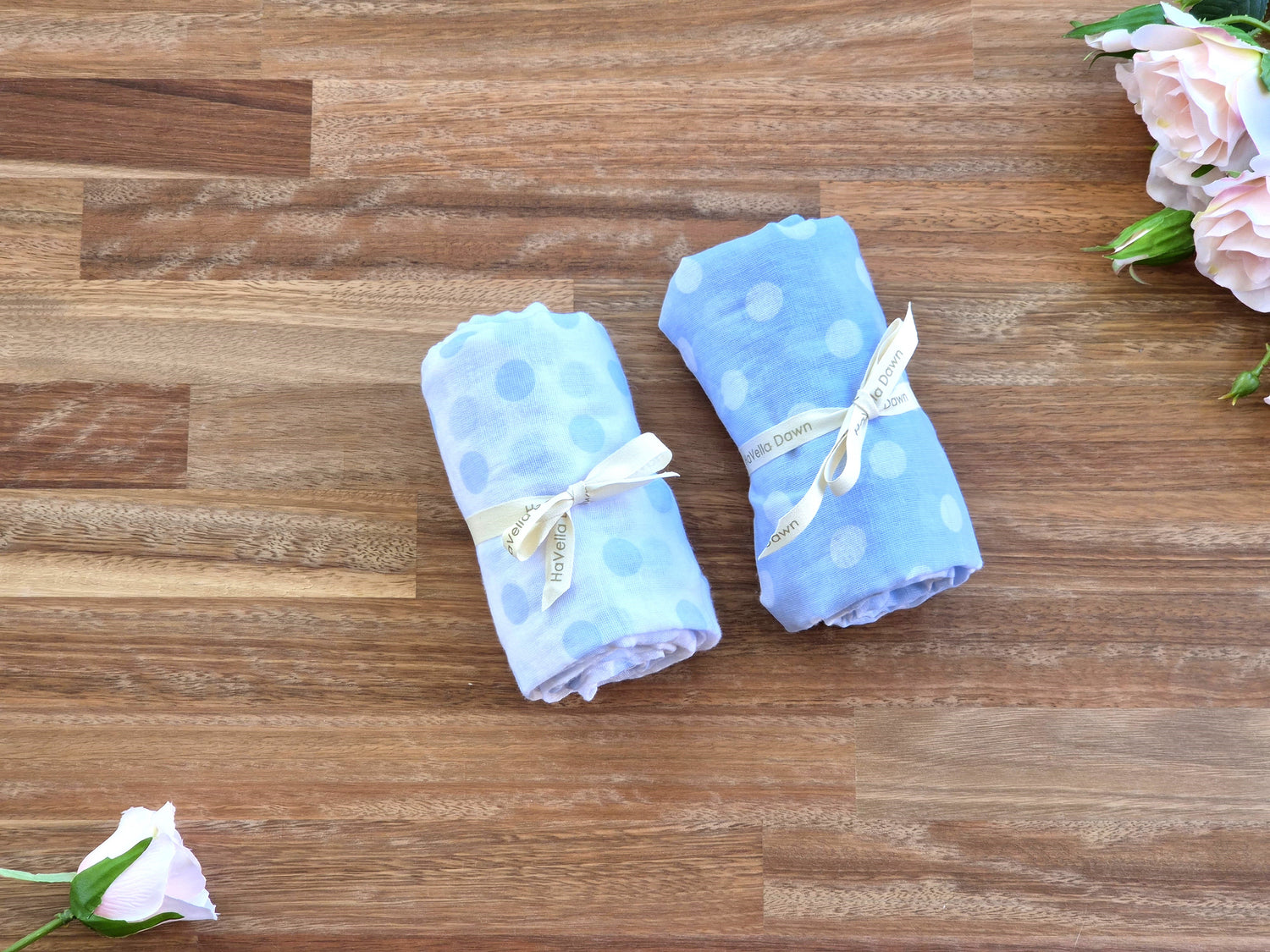 Two light blue polka dot baby blankets tied with white ribbon bows.