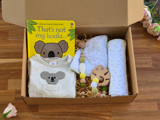 A baby gift box set containing baby romper with a koala face, a yellow 'That's not my koala sensory book, green spotty white wrap and matching bib, beaded teether ring and a matching beaded pacifier chain.